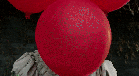 Pennywise face reveal behind a red balloon